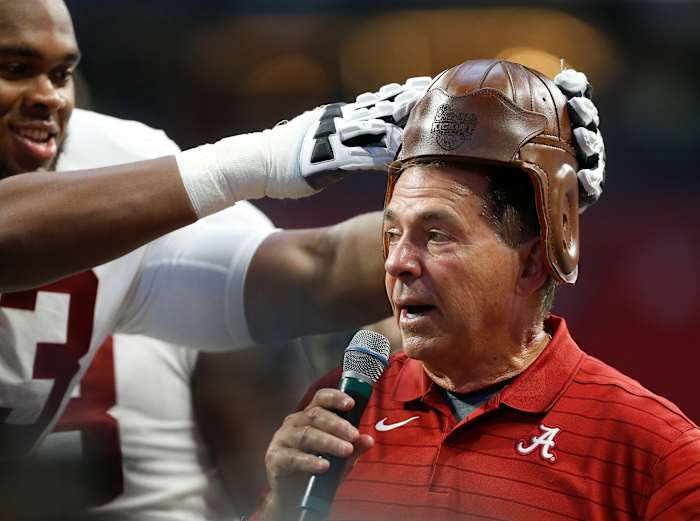 Alabama Crimson Tide offensive lineman Evan Neal (73) puts the old leather helmet on head coach Nick Saban at Mercedes-Benz Stadium after defeating the Miami Hurricanes.